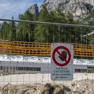 Prohibition sign on construction site barrier in front of mountain backdrop