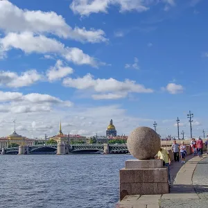 Promenade with people, red tower and city view under a blue sky