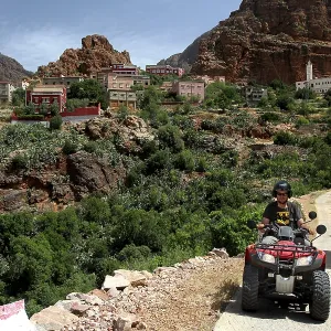Quad driver on a trail through a mountainous village and green surroundings