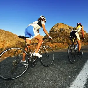 Two racing cyclists cycle uphill on the road