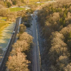 Railway line between trees and a country road in an autumn landscape Railway line between trees and a country road in an autumn landscape