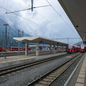 Railway Station and Red Train with Mountain View in a Cloudy Summer Day in Engadin