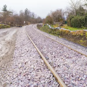 Railway tracks run curvy through a wooded landscape covered with gravel Railway tracks run curvy through a wooded landscape covered with gravel
