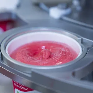 Raspberry ice cream in a cup during the filling process