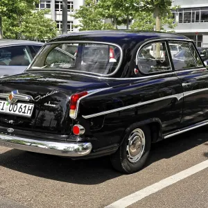 The rear view of a black classic car in a parking lot in sunny weather The rear view of a black classic car in a parking lot in sunny weather