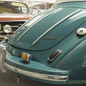 Rear view of a blue vintage car with chrome-plated bumper under a hall ceiling