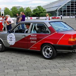 Rear view of a car with red accents at a lively classic car event