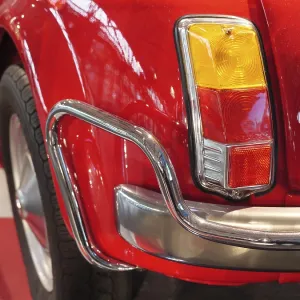 Rear view of a red classic car with shiny chrome bumper