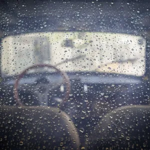 Rear window view into a classic oldtimmer with raindrops