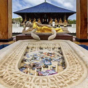 Reclining Buddha statue in a temple with coins in the foreground Reclining Buddha statue in a temple with coins in the foreground