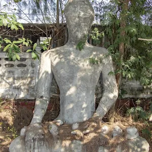 The reconstruction Buddha statue sitting under tropical tree