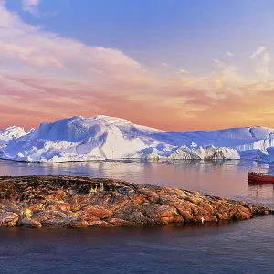 Red boat with tourists in front of icebergs in evening light Red boat with tourists in front of icebergs in evening light