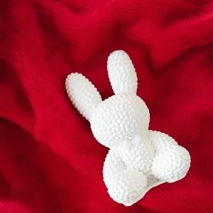 A red ceramic white rabbit lies on a red background A red ceramic white rabbit lies on a red background