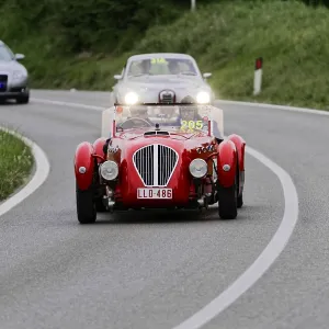 A red classic car on a winding road during a rally A red classic car on a winding road during a rally