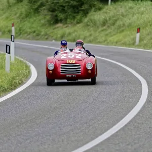 A red convertible sports car with two drivers on a winding country road A red convertible sports car with two drivers on a winding country road