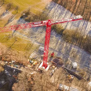 Red crane seen from the air on a construction site on the edge of a forest in an autumn landscape Red crane seen from the air on a construction site on the edge of a forest in an autumn landscape