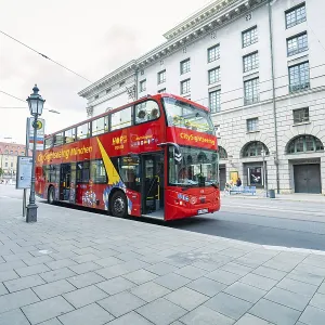 Red double-decker bus on a city street with historic buildings