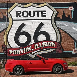 Red Ford Mustang convertible in front of the mural with the motif Route 66 Red Ford Mustang convertible in front of the mural with the motif Route 66