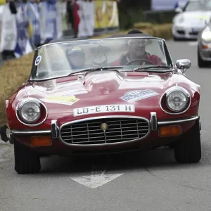 A red Jaguar E-Type convertible drives on a closed-off race track A red Jaguar E-Type convertible drives on a closed-off race track