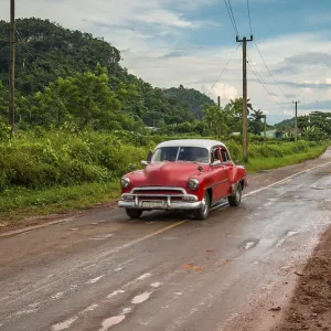 Red old american car drive on rural road in Cuban mountains