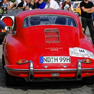 Red Porsche from behind, lots of people and vehicles at a classic car rally