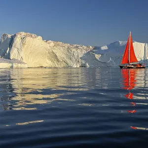 Red sailing boat in front of icebergs
