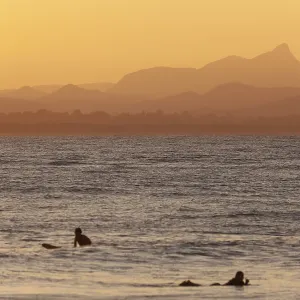 Red sunset on Wategos Beach with surfers in the ocean Red sunset on Wategos Beach with surfers in the ocean