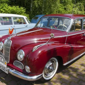 Red vintage car from the 50s in a car park in front of a forest Red vintage car from the 50s in a car park in front of a forest