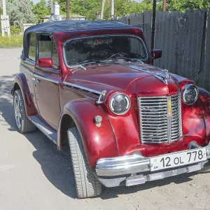 Red vintage car parked on a dusty road in the sunshine