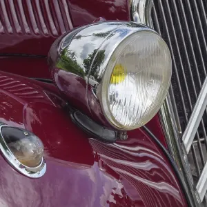 Red vintage car with round chrome headlights and chrome-plated details