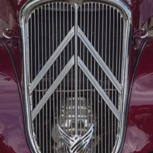 Red vintage car with vertical radiator grille and eye-catching emblem