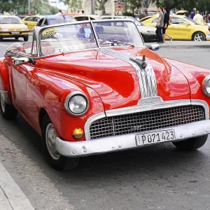 A red vintage convertible as a taxi on a busy city street with vivid colors A red vintage convertible as a taxi on a busy city street with vivid colors