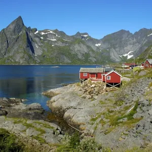 Red wooden house mountains and fjord Hamnoya Moskenesoya Lofoten Norway