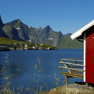Red wooden house mountains and fjord Hamnoya Moskenesoya Lofoten Norway Red wooden house mountains and fjord Hamnoya Moskenesoya Lofoten Norway
