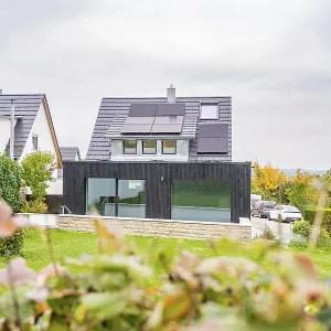 Residential building with black extension and glass front between neighboring houses Residential building with black extension and glass front between neighboring houses