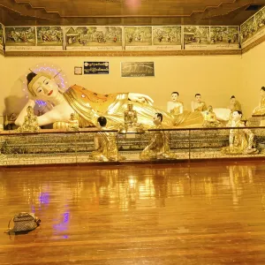 Resting Buddha statue in a gold-decorated interior with meditation participants