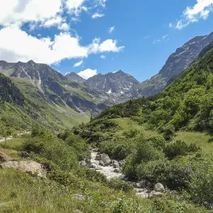 A river winds through a green valley between high mountains A river winds through a green valley between high mountains