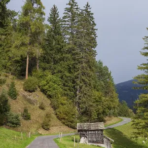 Road with forest and hay barn with dark clouds in the Stubai Valley between Telfes and Mieders