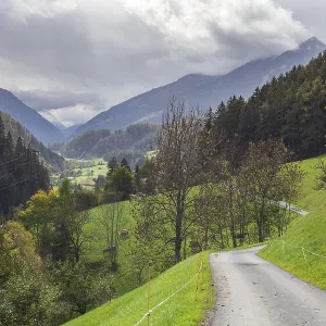 Road with mountains, dark clouds and forest in the Stubai Valley between Telfes and Mieders