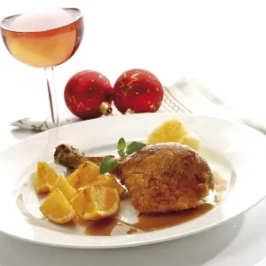 Roast turkey drumstick served on a white plate with orange slices