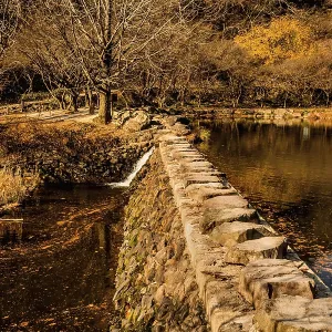 Rock footbridge across small lake on autumn morning