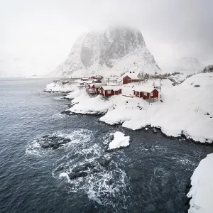 Rorbu fishing cabins on the snowy fjord in fog