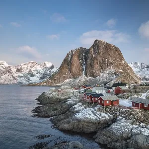 Rorbuer fishing huts in front of snow-covered mountains in winter Rorbuer fishing huts in front of snow-covered mountains in winter