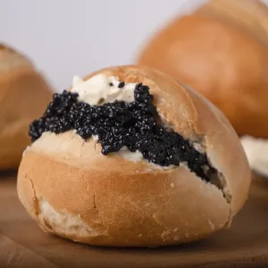 One round wheat bun with butter and black caviar One round wheat bun with butter and black caviar