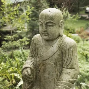 Ruined stone statue Ksitigarbha Bodhisattva in garden