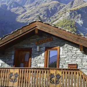 Rustic mountain hut with wooden balcony against an impressive mountain backdrop