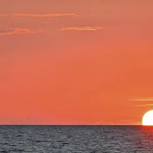 Sailboat sailing in the evening towards the setting sun Sailboat sailing in the evening towards the setting sun