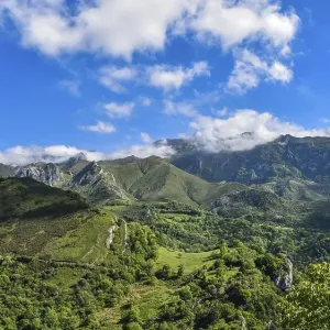 Scenic view of green hills and mountains under a bright blue sky with scattered clouds Scenic view of green hills and mountains under a bright blue sky with scattered clouds