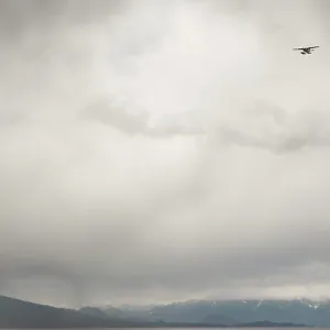 A seaplane flying against a backdrop of cloudy sky A seaplane flying against a backdrop of cloudy sky