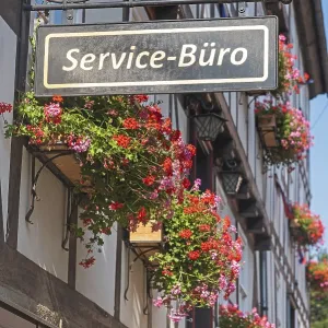 Service office, sign on a flower-decorated half-timbered house Service office, sign on a flower-decorated half-timbered house